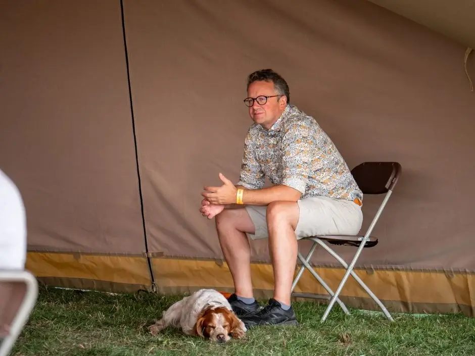 man sitting on a chair with a dog laying next to him