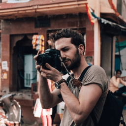 Micheal wearing a brown shirt taking a picture with a camera